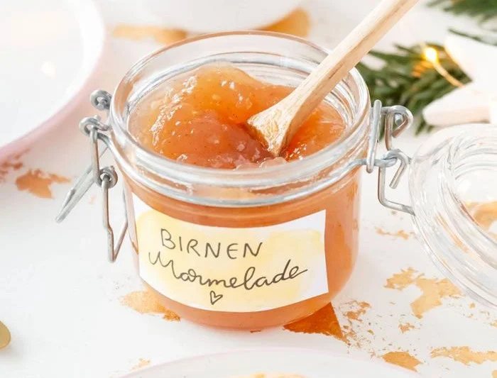 Glas Birnenmarmelade mit Vanille und Zimt auf einem Holzbrett