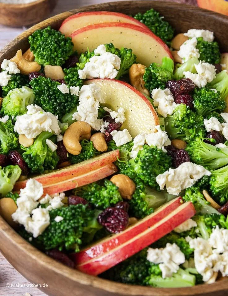 Brokkoli-Salat mit Äpfeln, Nüssen und Feta auf einem Teller serviert
