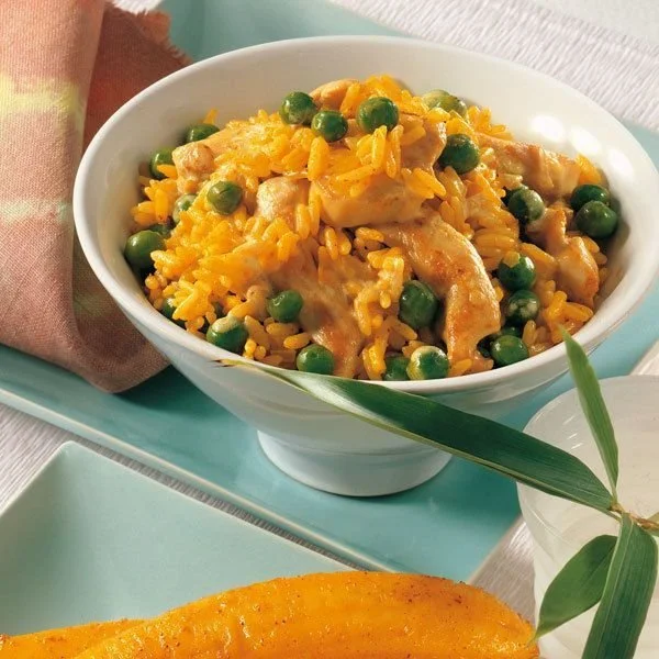 Curryreis mit Huhn und Erbsen auf einem Teller serviert