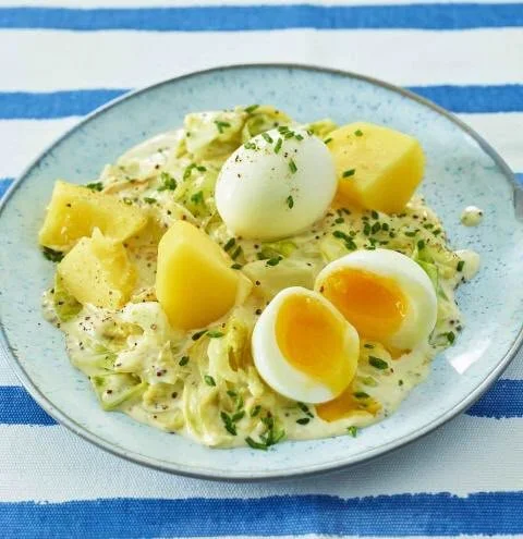 Senf-Rahm-Spitzkohl mit Kartoffeln und Ei auf einem Teller serviert