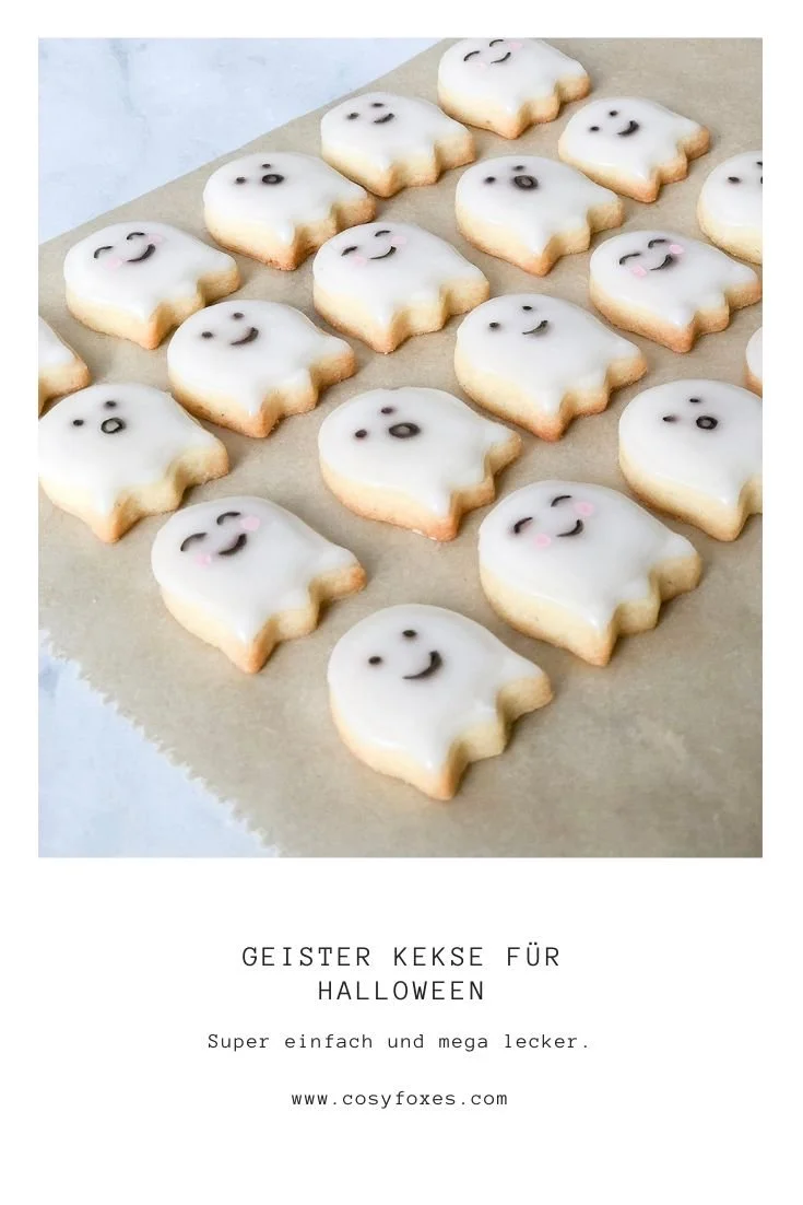 Halloween Kekse im Geistergewand auf einem Tisch dekoriert.