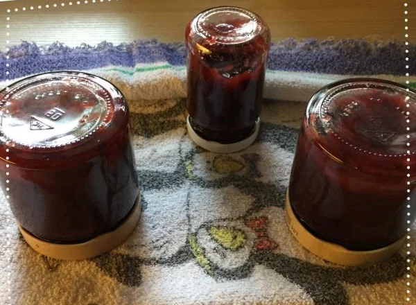 Hausgemachtes Pflaumenmus in einem Glas auf einem Holzbrett