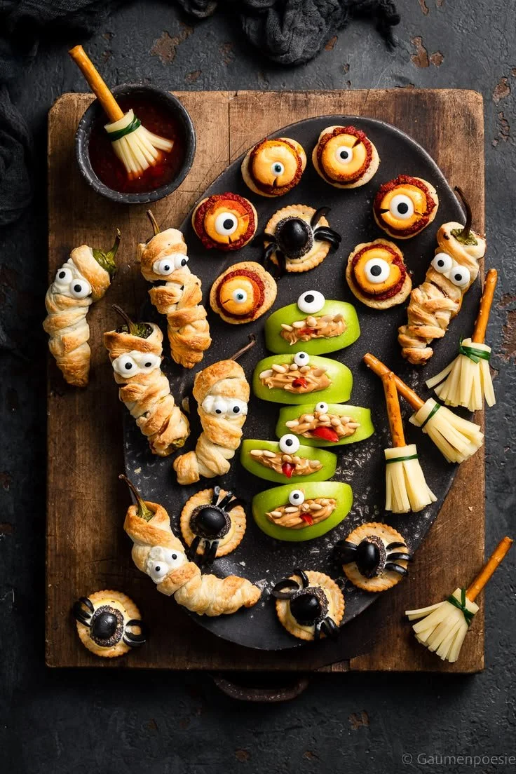 Gruselige Halloween Käse-Platte mit verschiedenen Käsesorten und Dekorationen