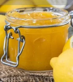 Hausgemachte Zitronenmarmelade im Glas mit frischen Zitronen