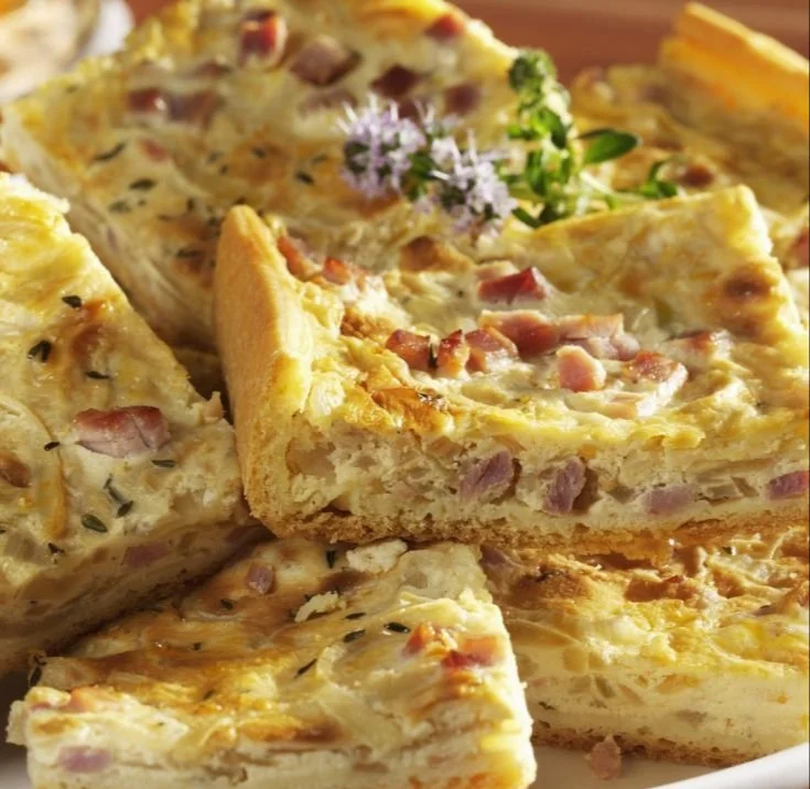 Leckerer Zwiebel-Speck-Kuchen auf einem Holzbrett serviert