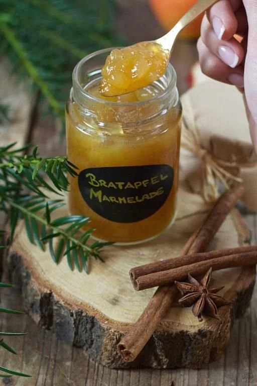 Glas mit Bratapfelmarmelade mit Amaretto auf einem Holztisch