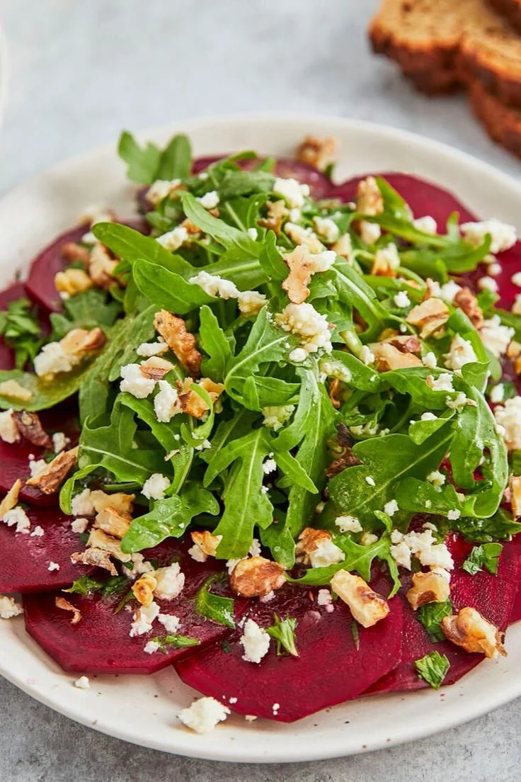 Rote-Bete-Carpaccio mit würzigem Dressing auf einem Teller serviert.